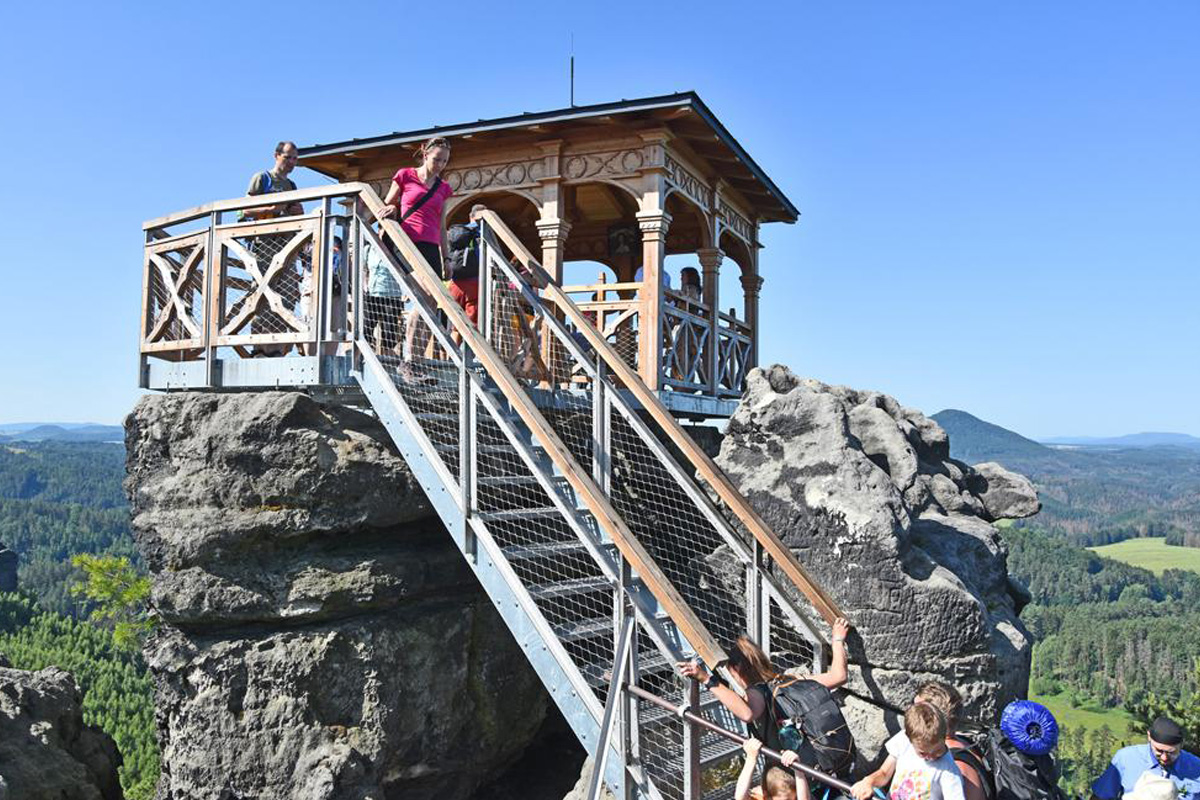 Zwei Radreisende machen ein Erinnerungsfoto vor der Rakotzbrücke im grünen Kromlauer Park.